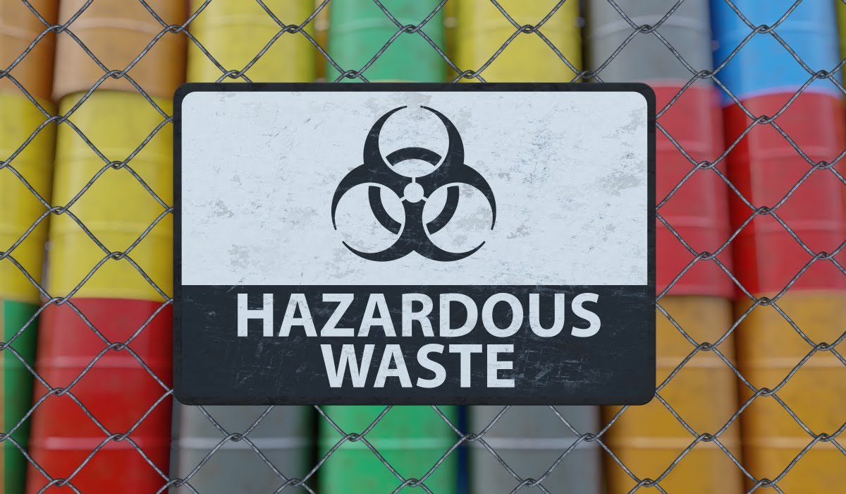 Hazardous waste sign in front of colorful barrels